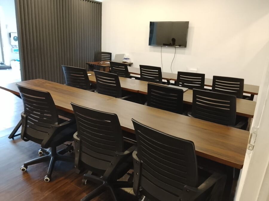 A classroom with rows of desks, chairs and a wall screen