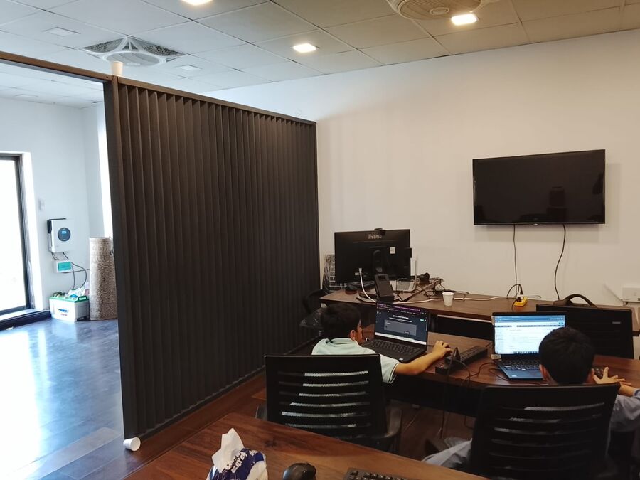 Two children working on laptops beside a partition wall